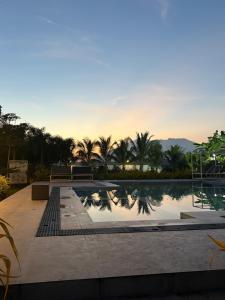 a pool with palm trees and a sunset in the background at Affordable Room in Angeles