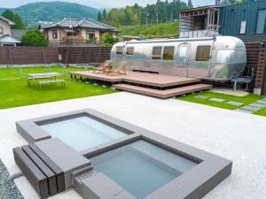 Un patio trasero con piscina y un remolque. en FOG villa&spa, en Kirishima