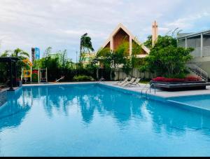 a large blue swimming pool with chairs and a building at Solea Tropical Suite in Davao City
