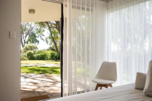 a bedroom with a bed and a white chair next to a window at 2 CapeView Beachfront Geographe Bay in Broadwater