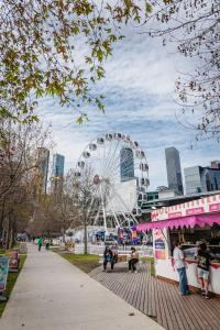 a ferris wheel in a park next to a city at Melbourne Central Gem in Melbourne