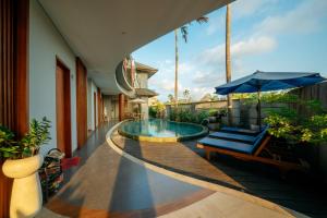 a swimming pool with a bench and an umbrella at ODA Guest House Umalas in Kerobokan