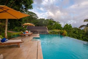 a pool with chairs and umbrellas next to a resort at Mirage Kandyan Heights in Kandy