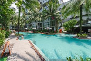 a large swimming pool with palm trees and a building at Diamond Resort Phuket walk to Bangtao Beach in Phuket
