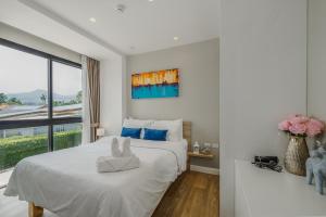 a white bedroom with a large bed and a window at Diamond Resort Phuket walk to Bangtao Beach in Phuket +17 photos