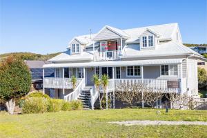 una casa blanca con un porche y un patio en 43 Squire Street Fingal Bay, en Fingal Bay