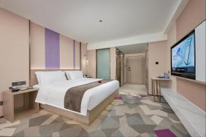 a bedroom with a large bed and a flat screen tv at 麗枫酒店广州番禺汉溪长隆大石地铁站店 in Guangzhou