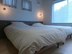 a large white bed in a bedroom with a window at 伊勢志摩パールヴィレッジ ヴィラ in Shima