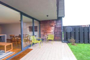 a patio with yellow chairs and a table on a patio at HOM I Frente a la Costanera Depto Familiar 3D2B in Puerto Varas
