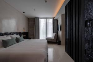 a hotel room with a large bed and a chair at Hôtel de Soie in Danang