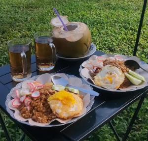 two plates of food on a table with drinks at Luxury Camp Waduk Darma in Haurkuning