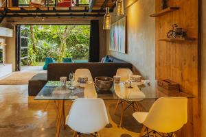 a dining room with a glass table and yellow chairs at Berawa Loft by Betterplace in Canggu