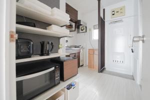 a small kitchen with a microwave and a stove at Encounter Ohashi in Fukuoka