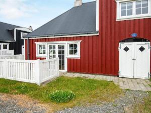 a red house with a white fence next to it at 4 star holiday home in Ringkøbing in Ringkøbing