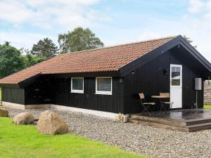 a black cottage with a cat sitting in front of it at 5 person holiday home in Otterup in Otterup