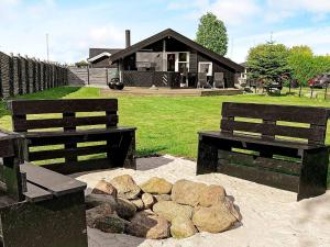 two benches in front of a house with a pile of rocks at 5 person holiday home in Otterup in Otterup +17 photos