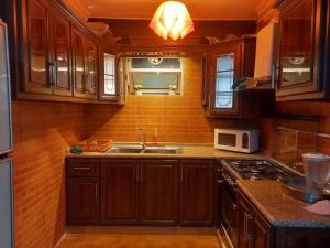 a kitchen with wooden cabinets and a sink and a microwave at Luxury furnished apartment for rent - شقة فاخرة مفروشة للإيجار in Amman