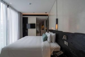 a bedroom with a large white bed and a mirror at Hôtel de Soie in Danang