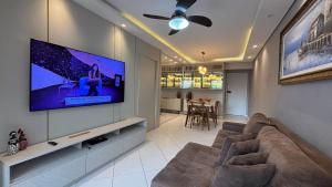 a living room with a couch and a flat screen tv at Apê central BC | 450m da praia + A/C + vaga in Balneário Camboriú
