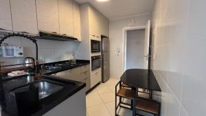 a kitchen with a sink and a counter top at Apê central BC | 450m da praia + A/C + vaga in Balneário Camboriú +14 photos