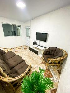 a living room with two chairs and a flat screen tv at Casa a 400m do Mar - O endereço correto é o Rua Rubens Marcus Rocha 541 Jd Jamaica Itanhaem in Itanhaém