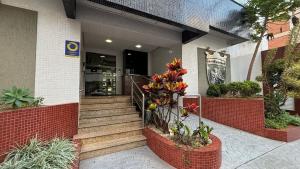 a building with stairs and flowers in front of it at Apê central BC | 450m da praia + A/C + vaga in Balneário Camboriú