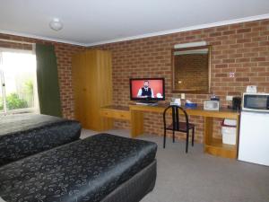 a living room with a tv and a bed at Inverloch Central Motor Inn in Inverloch