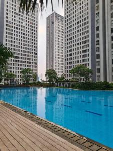 a large blue swimming pool in a city with tall buildings at M-town residence cozy apartment gading serpong in Pumpangsineng