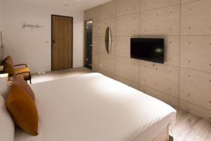 Un dormitorio con una gran cama blanca y un televisor. en Yunhua B&B, en Hualien City 33 fotos más