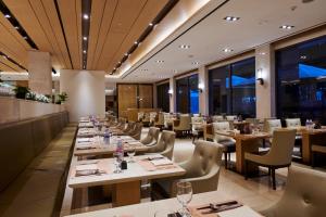 a restaurant with long tables and chairs and windows at Hotel Hyundai by Lahan Ulsan in Ulsan