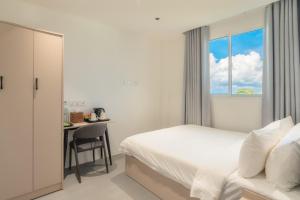 a bedroom with a bed and a desk and a window at Nest by Hawks Hotels Kamadhoo Baa Atoll in Kamadhoo