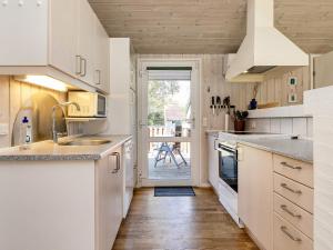 a kitchen with white cabinets and a wooden floor at 4 star holiday home in Hals in Hals