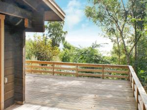 a wooden porch with a wooden fence and trees at 6 person holiday home in Rudkøbing in Spodsbjerg