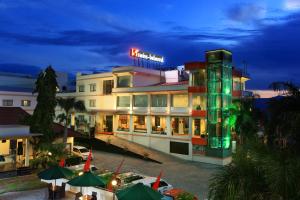a hotel building with a neon sign on top of it at Swiss-Belhotel Silae Palu in Palu