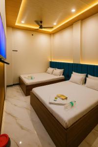 two beds in a room with a tv at Hotel Sindur in Ujjain