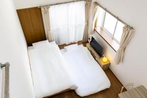 a small bedroom with two beds and a television at IL Regalo Tenjin Street Stay in Fukuoka