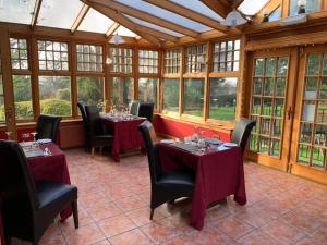 a dining room with tables and chairs and windows at Dunmar House Hotel - Bar & Restaurant in Alloa