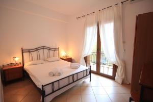 a bedroom with a bed with white sheets and a window at Eden Apartments in Neo Klima