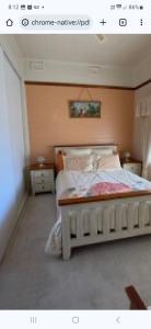 a bedroom with a large bed with a wooden headboard at Aeris Country Cottage in Junee