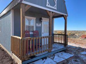 a small house with a porch with red chairs on it at Denim and Diamonds in Cane Beds