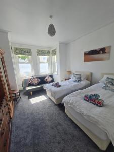 1 dormitorio con 2 camas, sofá y 2 ventanas en Sobo Retreat, en Iford