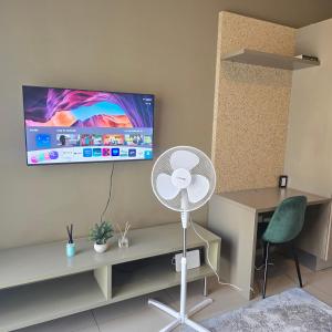 a room with a fan and a tv on the wall at Atrium Oasis, Sandton in Johannesburg