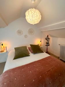 a bedroom with a large bed and a chandelier at Maison Simone in Samois-sur-Seine