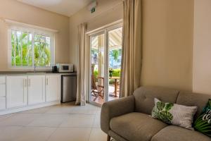 Una sala de estar con un sofá y una cocina. en Kisana Residence - Pleasant apartment with pool, close to beach, en Pointe aux Cannoniers