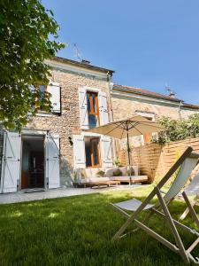 a patio with an umbrella in the yard of a house at Maison Simone in Samois-sur-Seine