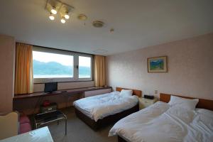 a hotel room with two beds and a window at Grand Hotel Taiyo in Shioura