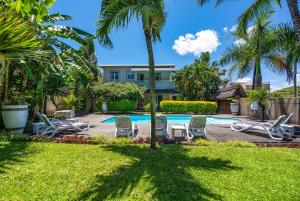 Una piscina tipo resort con tumbonas y palmeras. en Kisana Residence - Pleasant apartment with pool, close to beach, en Pointe aux Cannoniers