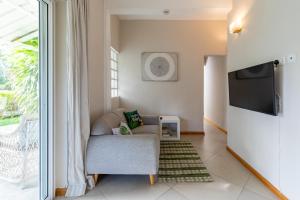 sala de estar con silla y TV de pantalla plana en Kisana Residence - Pleasant apartment with pool, close to beach, en Pointe aux Cannoniers