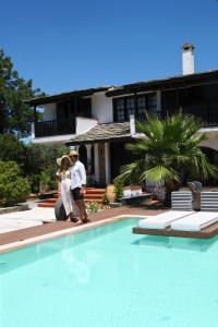 a man and a woman standing next to a swimming pool at Byblos Luxury Villa in Prinos