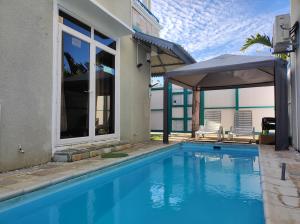 a swimming pool with an umbrella next to a house at Piscines Privées et Chauffées, Private Heated Pools in Grand-Baie